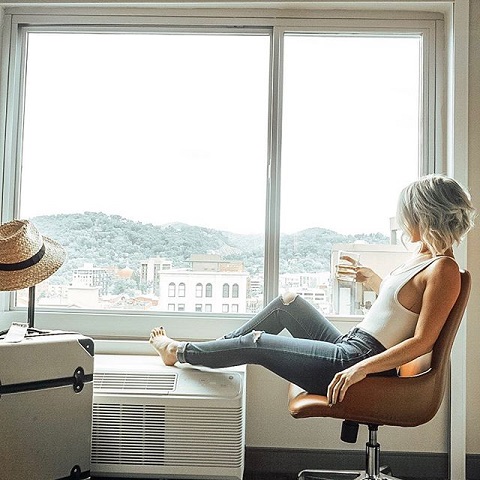 woman sitting by window in guest room at Cambria in Asheville