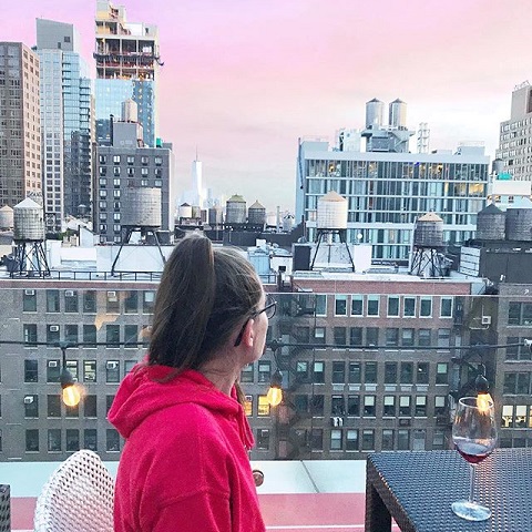 woman drinking wine at rooftop table at Cambria Hotel in Chelsea New York