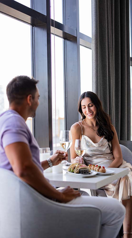 man and woman sitting next to a window eating dinner