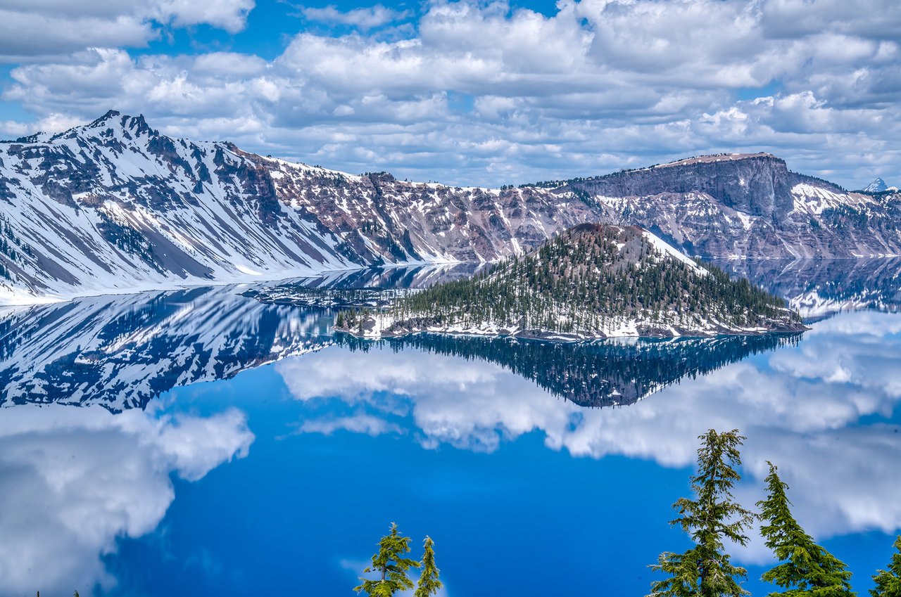 Snowy Wizard Island and caldera cliffs over sparkling Crater Lake, Oregon.